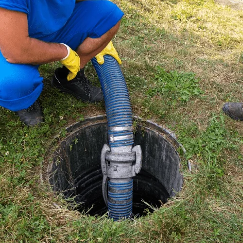 Vacuum hose lowered into an open septic tank during a residential pump out